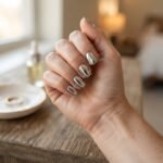 Close-up of silver mirror chrome nails in a short square shape on a realistic hand, liquid-metal finish in soft daylight