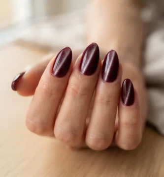 Close-up of deep burgundy velvet nails on almond-shaped nails showing the plush shifting shimmer effect