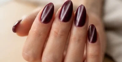Close-up of deep burgundy velvet nails on almond-shaped nails showing the plush shifting shimmer effect