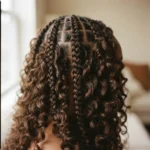 Close-up of a finished set of medium knotless boho braids on a Black woman with 4C natural hair, showing deep wave curly extension pieces woven throughout the length of each braid in soft natural window light.