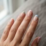 Close-up of five nails with colored french tips in soft pastel shades including lavender, sage green, and blush pink on a natural light-medium skin tone hand against a clean white background.