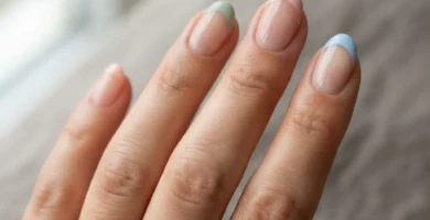 Close-up of five nails with colored french tips in soft pastel shades including lavender, sage green, and blush pink on a natural light-medium skin tone hand against a clean white background.