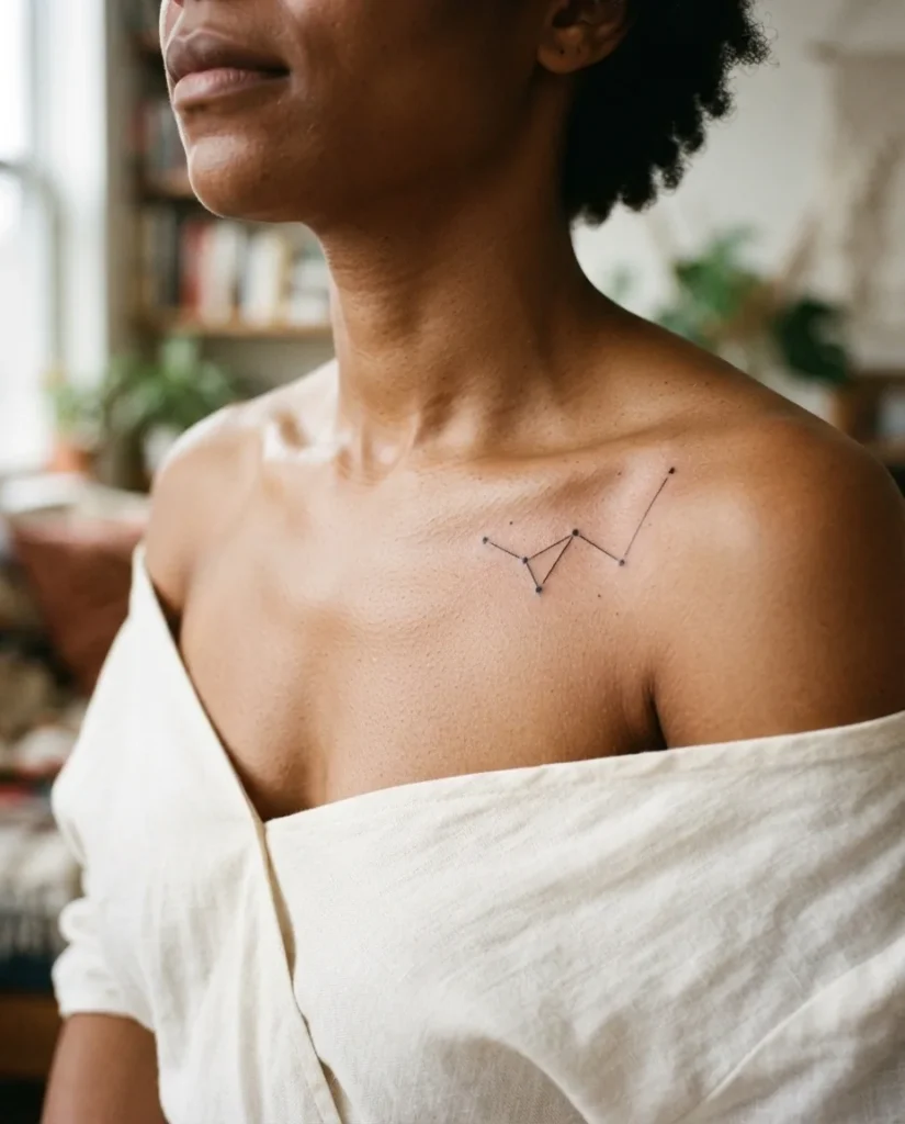 Close-up of a healed minimalist constellation tattoo along the collarbone of a young woman, featuring fine black dot-work stars and connecting lines on medium skin tone in soft natural light.